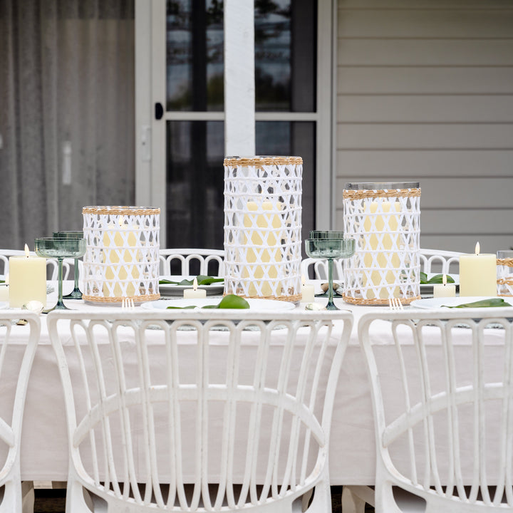 Outdoor dining setup with white chairs and a long table, featuring decorative items.